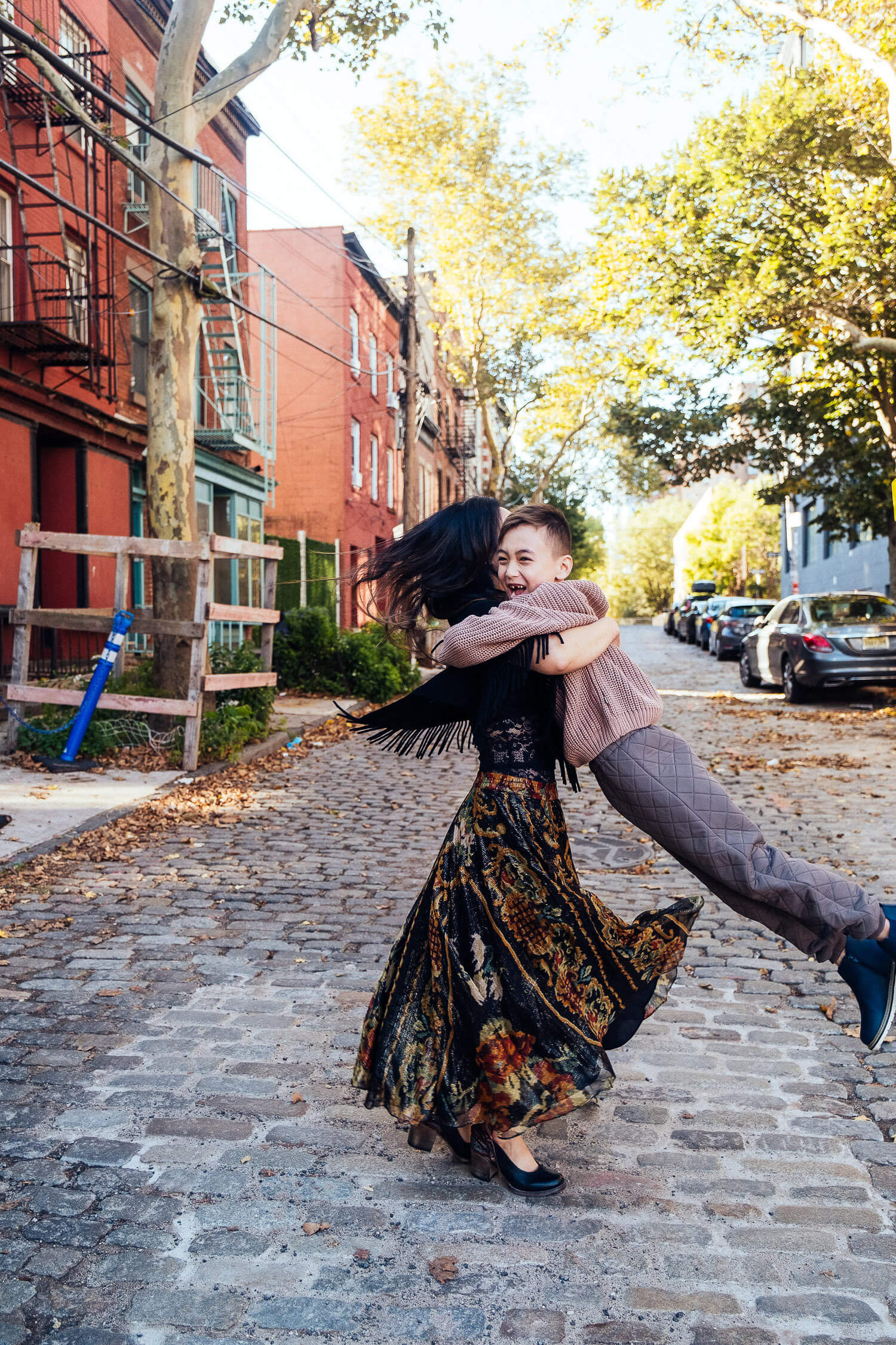 Cobble stone street in Dumbo. Mom and son laughing. 