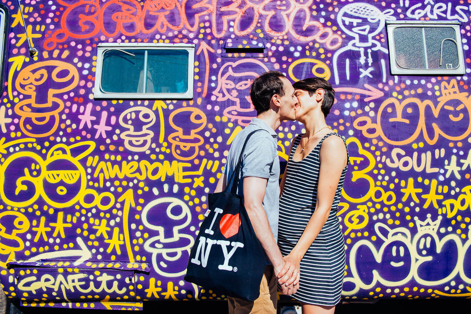 pregnant mom kissing her husband in front of a cool van caravan