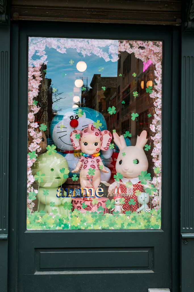 n.mé kids boutique spring window display with Doraemon Sonny Angel and Sylvanian Families figures cherry blossoms and shamrocks West Village New York City