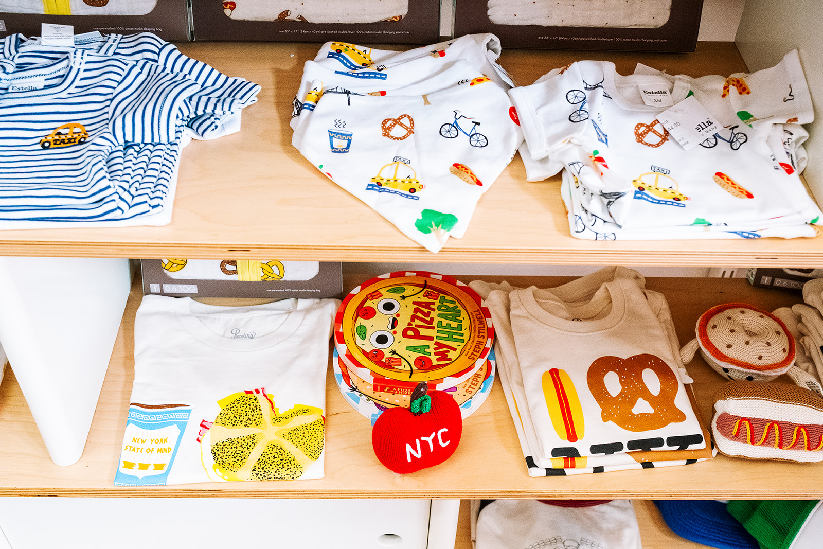NYC themed baby and kids clothing with pretzel hot dog and taxi prints alongside childrens books at Babesta kids store TriBeCa New York City