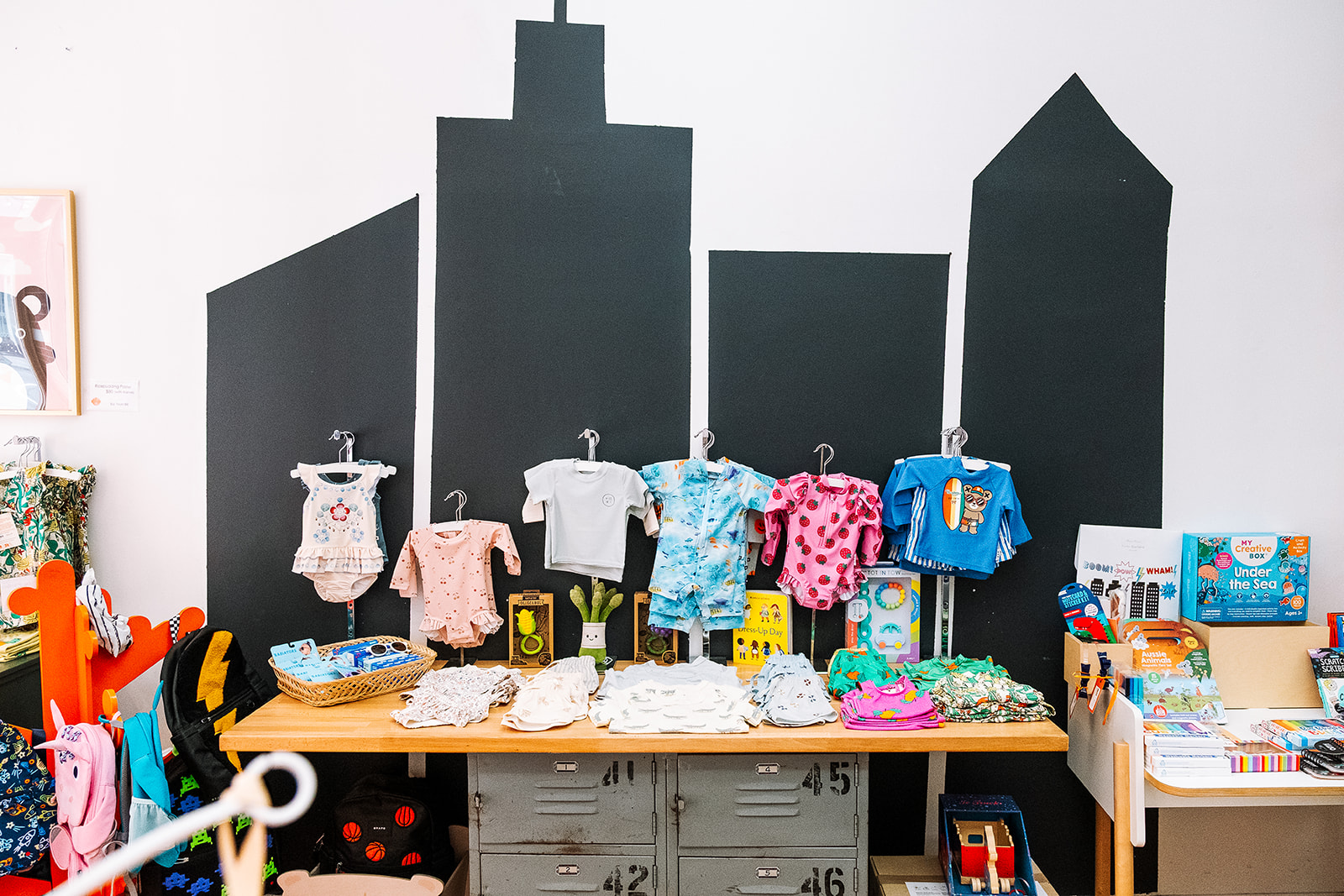 Baby and kids clothing display against a painted NYC skyline mural at Babesta childrens store