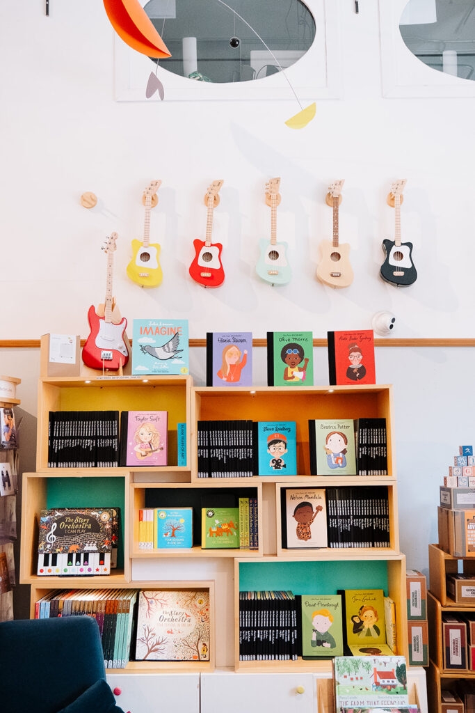 Wall display of toy guitars and inspiring biography childrens books including Taylor Swift and Ruth Bader Ginsburg at Mini Jake Brooklyn