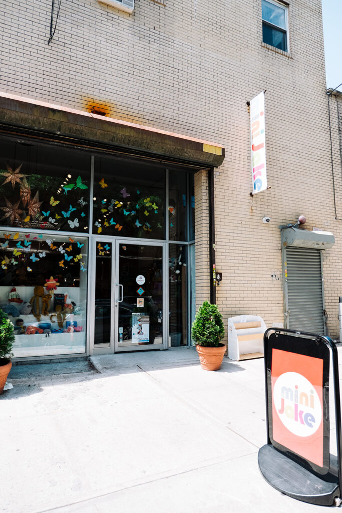 Mini Jake kids store exterior with butterfly window decorations and sandwich board sign on sidewalk Brooklyn New York City