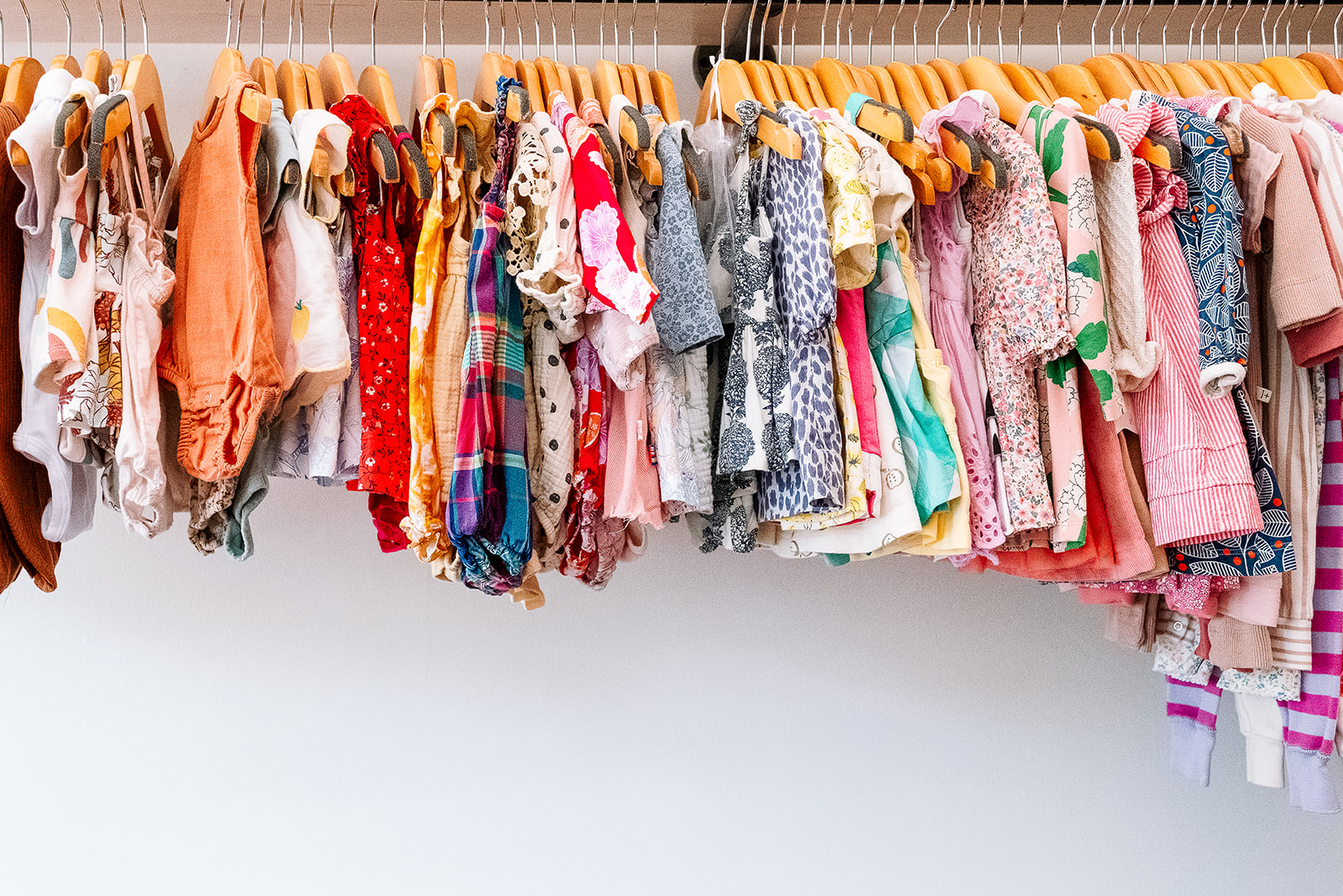 Full rack of colorful baby and kids clothing on wooden hangers at Parachute Brooklyn Greenpoint New York City