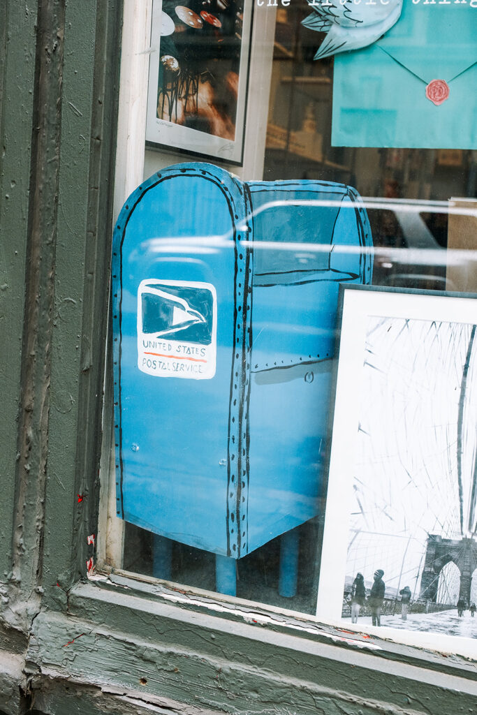 Hand painted USPS mailbox illustration in the window display at Pink Olive gift boutique West Village New York City